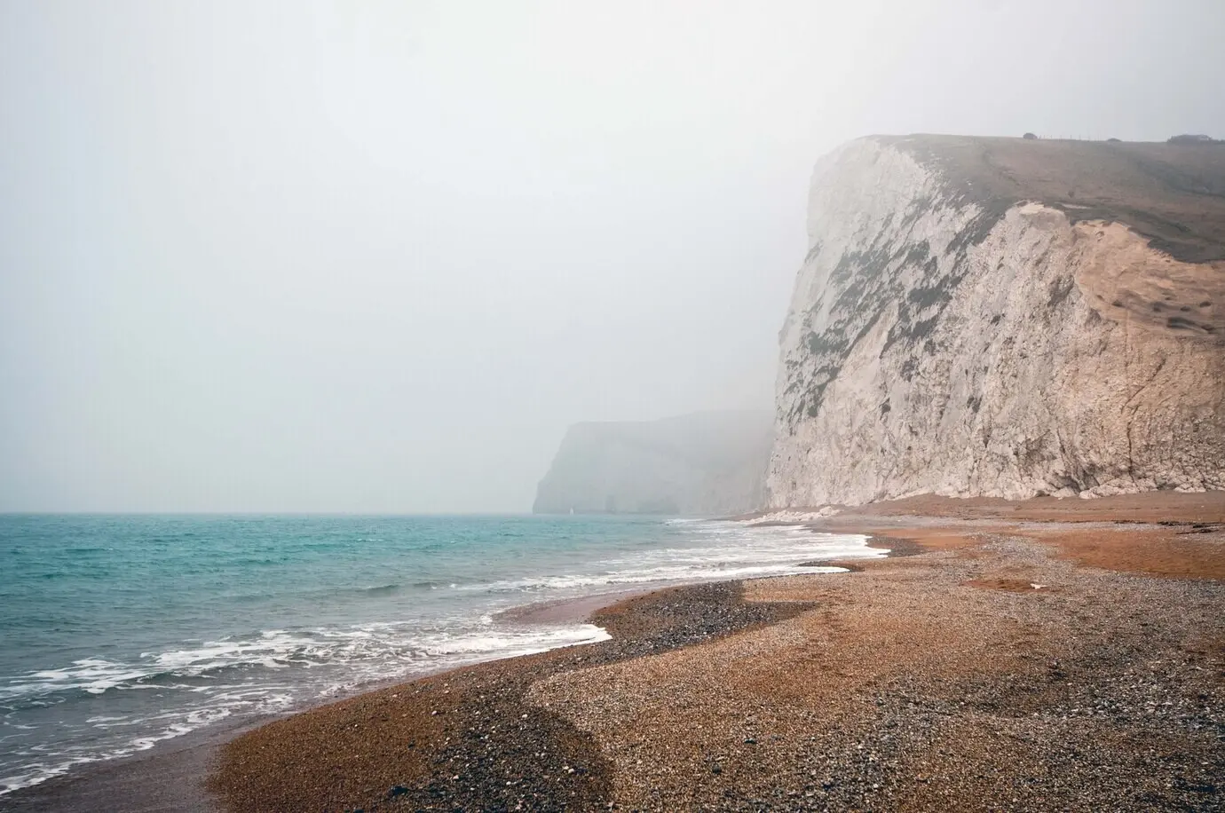 Faszinierender Ausblick auf den ruhigen Ozean an einem nebligen Tag an der Purbeck Heritage Coast in Swanage, UK.